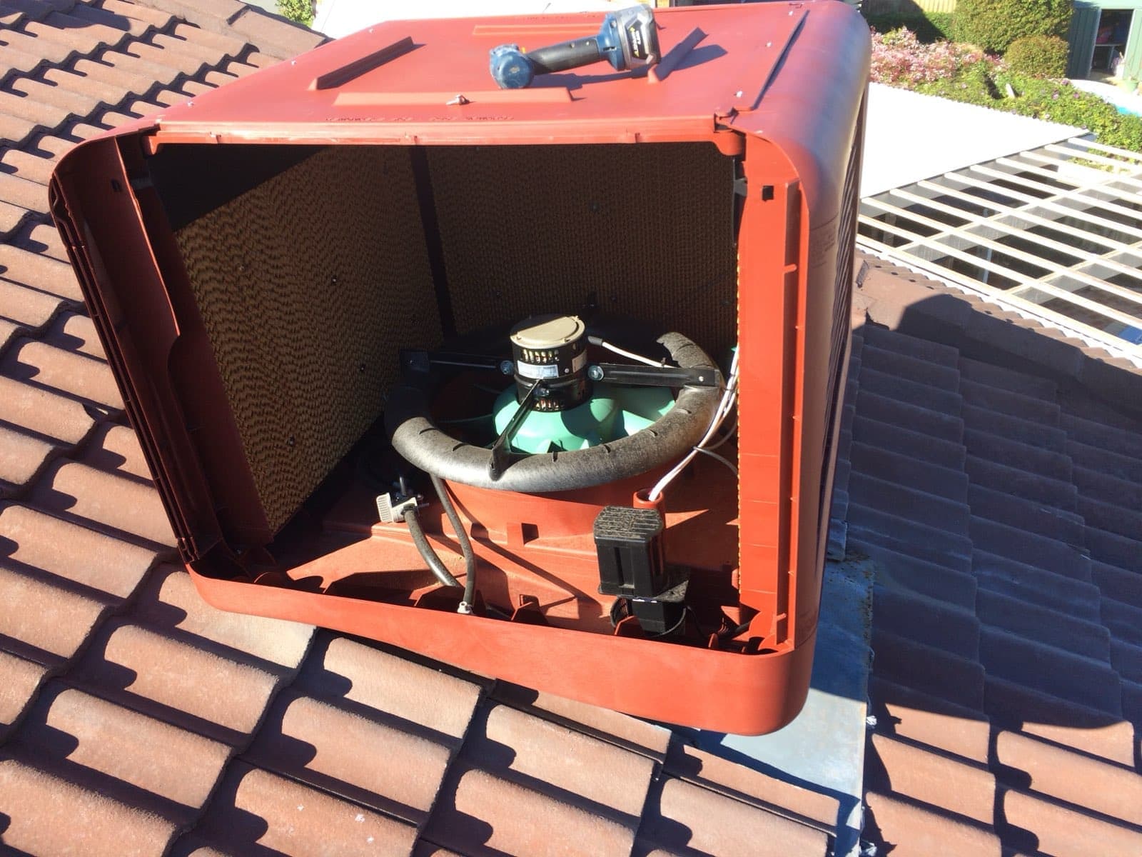 Evaporative cooler opened for servicing, showing the cooling pads, fan, motor and water distributor